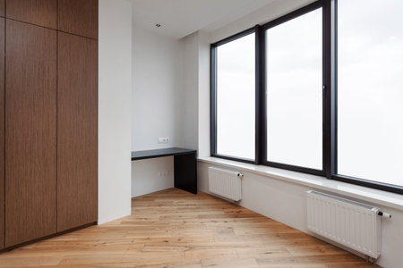 empty room in renovated apartment. balcony with modern interior, wooden closet, home office desk, window, white wall and laminate floor in flat, rent of real estateの写真素材