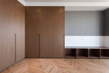 renovated room with wooden cabinet, laminate floor and grey wall. buying new real estate in residential building. wardrobe with natural material in living roomの写真素材