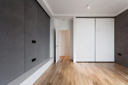 bedroom in stylish apartment after refurbished. room with natural wood laminate on floor, wall with grey tones and modern white wardrobe for storage clothingの写真素材