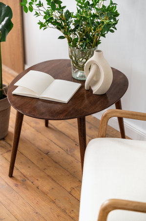 Vertical shot of stylish retro composition with journal book on brown side table near armchair. Personal diary with empty pages, ceramic and glass vases on wooden countertop.の写真素材
