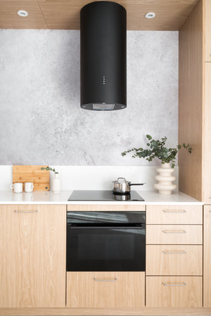 modern kitchen interior in apartment, wooden cabinet with integrated electric oven and glass ceramic cooker top, white countertop and hood extractorの写真素材