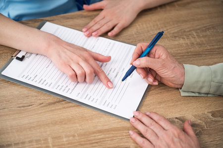 Elderly patient filling insurance at appointment with doctor in hospital or private clinic. Woman...