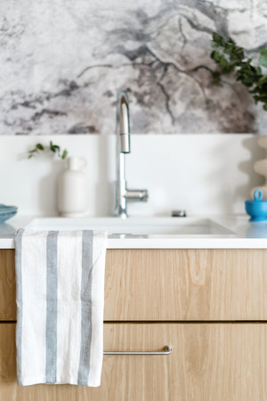 selective focus on striped towel from cotton fabric hanging on countertop near sink with chrome faucet at stylish kitchenの写真素材