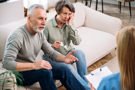 Anxious mature couple sitting on couch, listening doctor explaining prescription, test results, diagnosis, treatment plan. Private clinic or home visit, modern healthcare conceptの写真素材