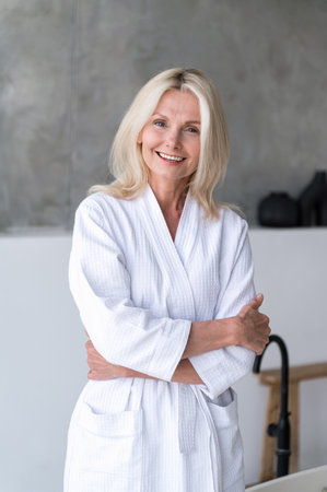 Relaxed happy mature woman after salon spa procedures on weekend. Portrait of smiling female client in robe with fresh, clean, soft skin. Body and skincare, beauty treatment, wellness concept.の写真素材