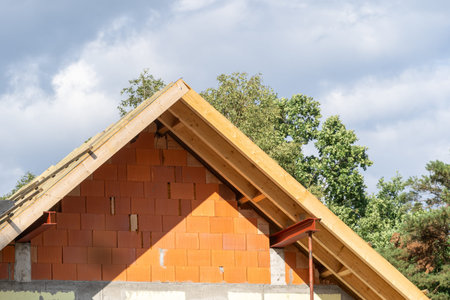 Waterproof layers on gable truss roof top with boards and planks. Attic elements on new brick house...
