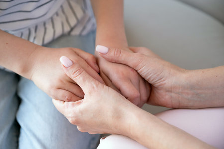 Closeup on young loving caring mother holding hands of kid girl, support and give comfort. Woman...