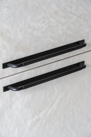 Vertical shot of gray textured facade of the wardrobe door in the bedroom. Close up view of black metal handle of kitchen cabinet. New modern furniture in contemporary apartment with expensive designの写真素材