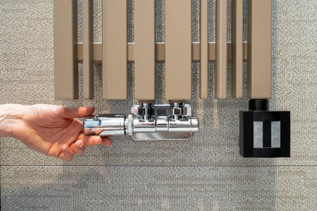 Cropped view on woman hand adjusting temperature with thermostat regulator on modern radiator at...