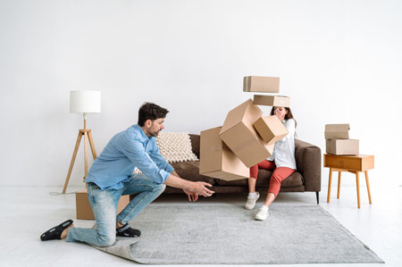 Adult man trying to catch cardboard boxes with personal staff falling on floor in living room....