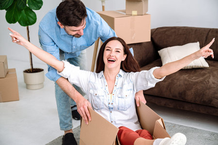 First time home buying, moving day concept. Happy young couple having fun, unpacking things in new...