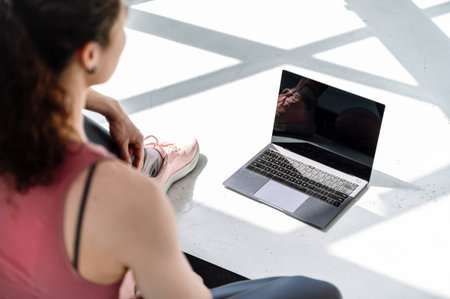 Selective focus on laptop screen with copy space. Young woman in activewear watching online fitness...