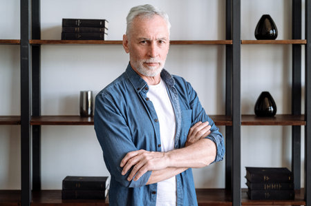 Headshot portrait of confident man in casual wear looking at camera, standing in living room at home...
