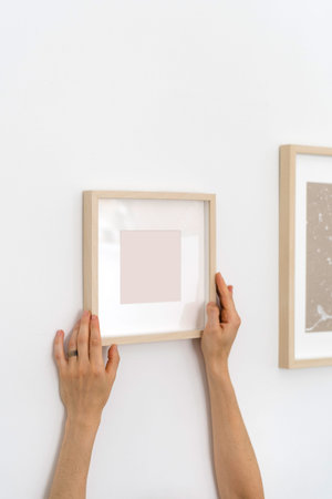 Cropped shot of woman holding wooden picture frame in hands. Vertical shot of female with copy space...