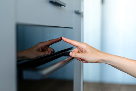 Cropped view on woman hand press sensor button of modern electric oven to cooking dinner. Female...