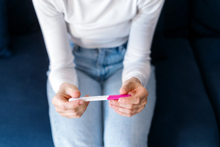 Woman checking at result on confirmed pregnancy test, making hard decision about abortion unwanted or unplanned child. Concept of birth control, reproductive healthの写真素材