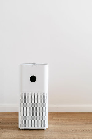 Electronic air purifier from allergens, virus and dust pollution in living room with white copy...