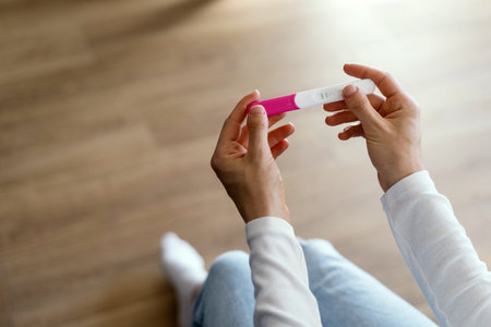 Close up cropped shot of woman holding pregnancy or ovulation test kit in hands, checking results....