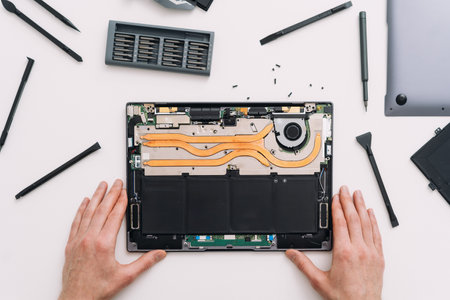Repairman change battery in laptop. Engineer install new hard drive disk in computer, flat lay. Man fixing broken notebook in warranty service, table top view. Technician upgrade computer componentsの写真素材