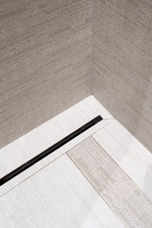 Modern linear flow drain on floor in shower cabin with tiled wall at luxury bathroom. Minimalist style. Water disposal system. Drainage at domestic washroom.の写真素材