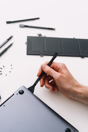 Man open laptop cover using special hand tool, high angle view. Diagnostic notebook, recovery broken computer. Maintenance, repair and warranty service for modern technologyの写真素材