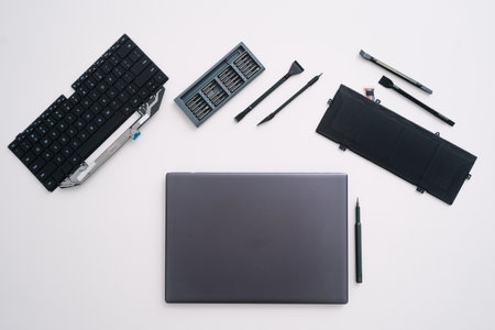 Flat lay of modern laptop on white table surrounded with tools for repair. Top view of computer in warranty service center. Hardware maintenance, recovery and upgrade component conceptsの写真素材