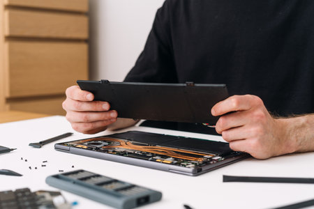 Basic warranty service of battery replacement. Technician man repair laptop and remove, replace and recycle old component on computerの写真素材