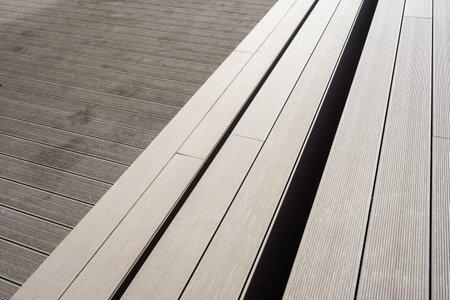 High angle view of composite decking boards, minimalistics wooden bench on yard. Stone walkway in cityの写真素材