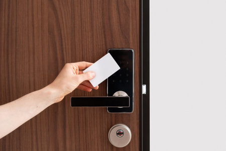 Cropped shot of woman hand hold a key card for self check-in at the hotel room. Person using wireless and keyless technology to open entrance door in apartmentsの写真素材