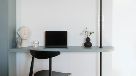 Wireless notebook on workspace. Modern netbook with mockup display. Home office with black chair close to blue desk, laptop computer and decor against white copy space backgroundの写真素材