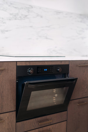 Modern electric oven with open door, hot air ventilation and microwave mode under stove. Household appliance built in wooden kitchen cabinet. Expensive interior design in apartment. Copy space wallの写真素材