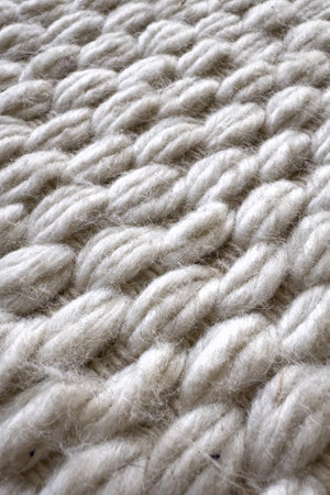 Dry cleaning service for home textile. Close-up shot showcasing the textured surface of a white knit carpet, highlighting intricate weave and soft appearance. Wool rug in bedroom, comfort livingの写真素材