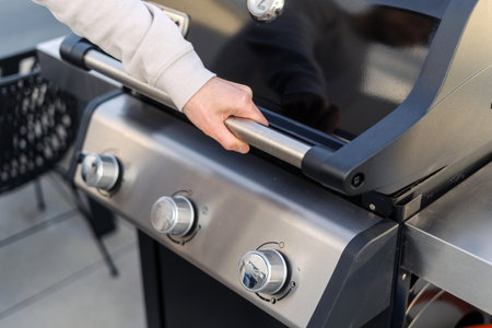 Man open lid and checking fire in bbq grill, looking if burned down to hot coals ready for cooking meat. Barbeque equipment, outdoors kitchen conceptsの写真素材