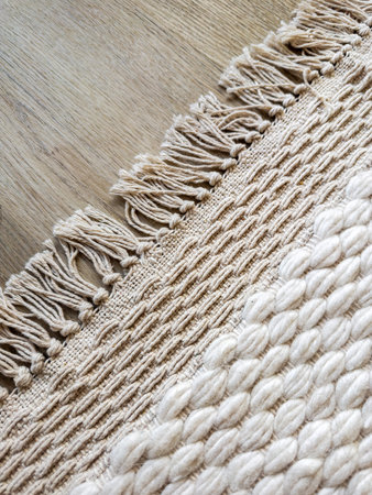 Top view of wool woven rug with fringe, intricate texture and pattern and soft surface. Carpet on...