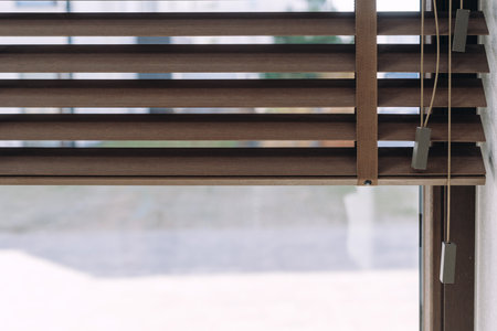 Detailed view of a brown blinds covering a window, showing the texture and pattern of the wood. Close up view of jalousie. Sunlight protection in living room or office. Modern shutters at homeの写真素材