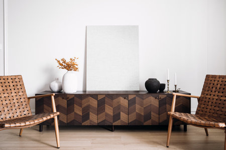 Modern composition of living room interior with design commode, stylish retro chairs, mock up picture frame and elegant vase with plants. Armchairs against wooden furniture with home decorationの写真素材