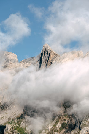 A striking mountain peak rises through white clouds, creating a peaceful moment against the vibrant...