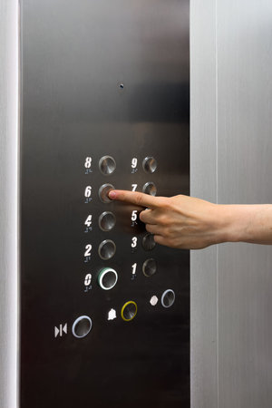 Cropped shot of woman hand reaches out to press the seventh floor button on a contemporary elevator...