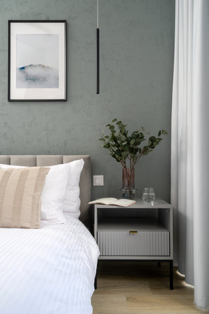 Bedroom featuring a comfort bed against a gray wall with art poster in picture frame. Home interior,...
