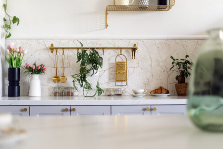 Selective focus on bright kitchen counter with home decor plants, flowers and utensils. Marble...