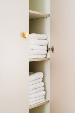 Soft white towels are neatly stacked on shelves in an organized wardrobe cupboard. This tidy space adds a touch of comfort and style to the modern bedroom interior design.の写真素材