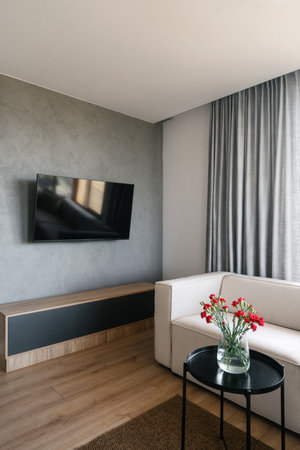 This living room features a sleek design with a white comfortable sofa, a beautiful flower...