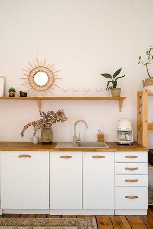 Vertical shot of modern, minimalist kitchen features a white cabinetry and countertop design,...