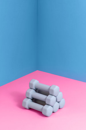 Brightly colored dumbbells are neatly stacked in a corner setting, offering a vibrant backdrop ideal for home workouts or gym training activities focused on fitness and health.の写真素材