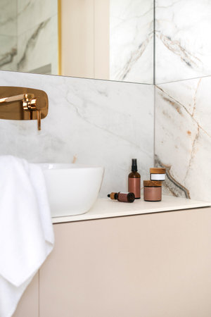 A well-designed bathroom features a white ceramic sink, elegant faucet, and neatly arranged skincare products, creating a cozy atmosphere for an enjoyable morning routine.の写真素材