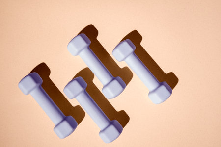 Brightly colored dumbbells are arranged on a smooth surface. Equipment for various workout routines and promoting a healthy lifestyle through exercise.の写真素材