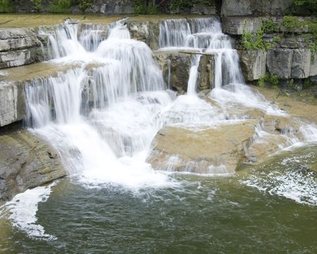 Flowing water over rocks forming a waterfalls.の写真素材