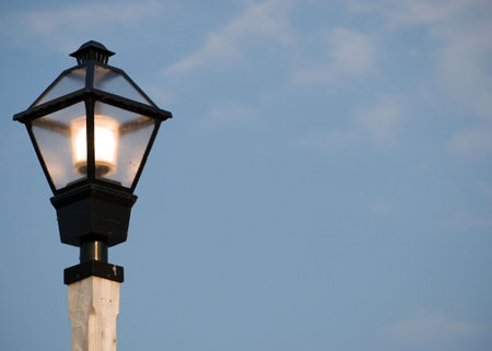 A lit up street light against a blue sky.の写真素材