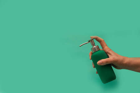 Woman holding soap dispenser on green backgroundの写真素材