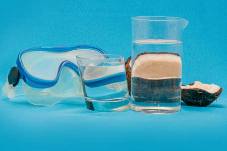 Diving mask and coconut halves distorted through glasses with waterの写真素材